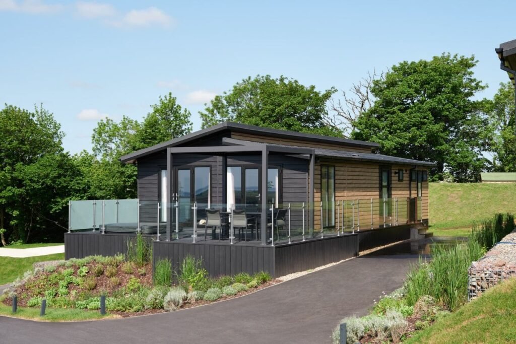 Modern timber-clad luxury lodge with covered terrace, glass balustrades and landscaped gardens at Dylan Coastal Resort.