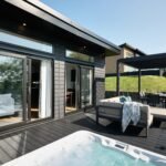 Private luxury lodge terrace overlooking the Taf Estuary, furnished with outdoor sofas, sun loungers and a hot tub.
