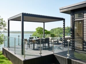 Luxury lodge terrace with pergola, outdoor dining furniture and glass balustrades overlooking the estuary at Dylan Coastal Resort.