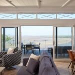 Open-plan luxury lodge lounge with sliding glass doors leading to a private terrace overlooking the Taf Estuary.