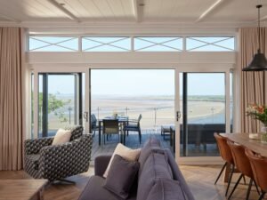Open-plan luxury lodge lounge with sliding glass doors leading to a private terrace overlooking the Taf Estuary.