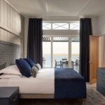 Double bedroom at Dylan Coastal Resort with patterned upholstered headboard and glass doors opening towards the estuary.