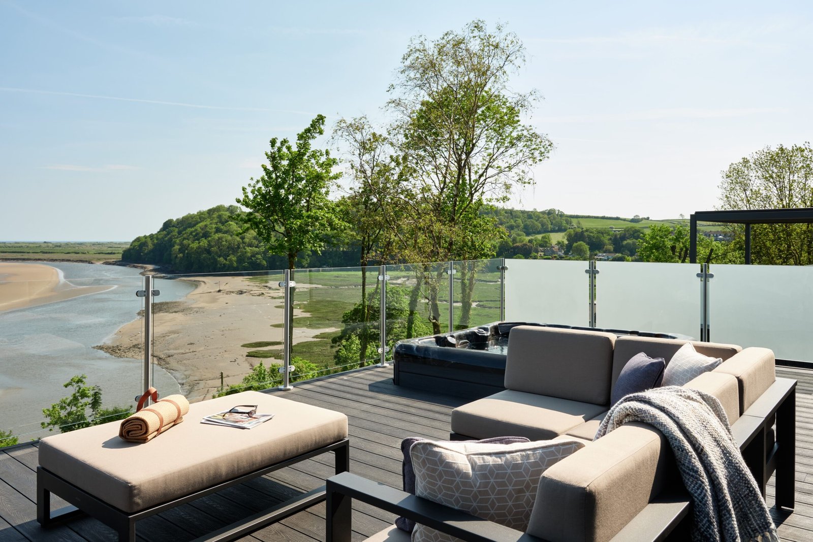 Luxury lodge terrace with pergola, outdoor dining furniture and glass balustrades overlooking the estuary at Dylan Coastal Resort.