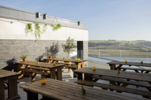 Outdoor dining terrace at Milk Wood Bar and Kitchen, with wooden picnic tables and views over the Taf Estuary.