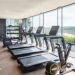 Technogym fitness suite at Milk Wood Spa, Dylan Coastal Resort, with floor-to-ceiling windows overlooking the Taf Estuary.