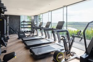 Technogym fitness suite at Milk Wood Spa, Dylan Coastal Resort, with floor-to-ceiling windows overlooking the Taf Estuary.