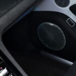 Close-up of a Naim audio speaker with an intricate circular grille inside the Bentley Torcal electric SUV.