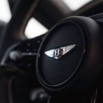 Close-up of the Bentley winged emblem on the black leather steering wheel of the Torcal electric SUV.