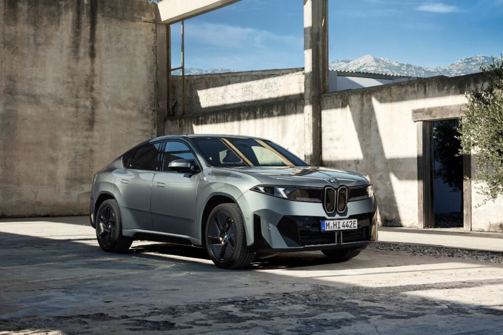 New BMW iX4 electric SUV photographed from a front three-quarter angle, showing its distinctive grille and coupé-style roofline.