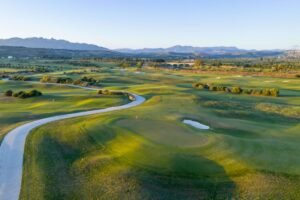 Aerial view across the championship golf course at Verdura Resort, with green fairways, bunkers and distant mountains.