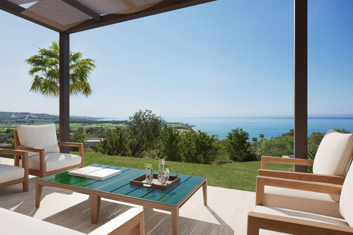 Shaded villa terrace with contemporary outdoor armchairs and a coffee table overlooking the Sicilian coastline.