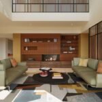 Luxury villa living room with sage-green sofas, a contemporary fireplace and a feature wall with built-in shelving.