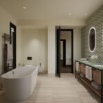 Contemporary bathroom with a freestanding bathtub, green marble double vanity and illuminated oval mirrors.