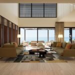 Double-height living room with contemporary seating and large sliding doors opening towards the Mediterranean Sea.