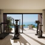 Private gym at Rocco Forte Verdura in Sicily, featuring fitness equipment and floor-to-ceiling windows overlooking an infinity pool and the Mediterranean Sea.