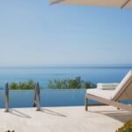 Private infinity pool overlooking the Mediterranean Sea with a cushioned sun lounger on the stone terrace.