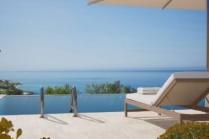 Private infinity pool overlooking the Mediterranean Sea with a cushioned sun lounger on the stone terrace.