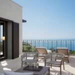 Private villa balcony with outdoor lounge chairs, a small coffee table and panoramic Mediterranean Sea views.