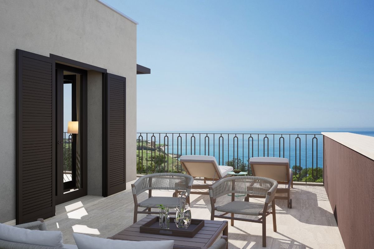 Private villa balcony with outdoor lounge chairs, a small coffee table and panoramic Mediterranean Sea views.