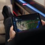 Passenger inside a SyberJet cabin holding a tablet displaying a flight route across the United States.