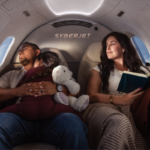 Family travelling in a SyberJet private jet cabin, with one passenger reading beside reclining seats.