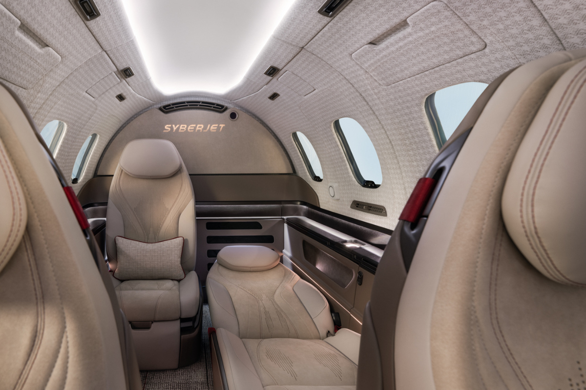 Rear seating area of the proposed SyberJet SJ36 interior with reclining cream leather seats and overhead lighting.