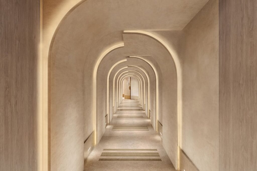 The spa arrival corridor at Waldorf Astoria London – Admiralty Arch, featuring illuminated arches and elegant neutral stone finishes.