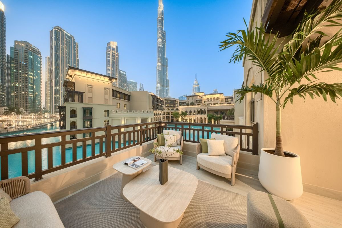 Outdoor seating area with cream armchairs, tropical planting and views towards the Burj Khalifa in Dubai.