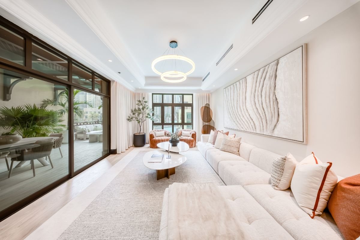 Contemporary living room with cream sofas, large abstract artwork and sliding glass doors opening onto the terrace.