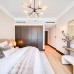 Elegant bedroom with a large upholstered bed, dark wood wardrobes and contemporary decorative lighting.