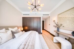 Elegant bedroom with a large upholstered bed, dark wood wardrobes and contemporary decorative lighting.