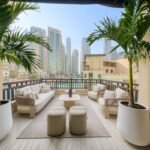 Luxury outdoor lounge with cream sofas, coffee tables and potted palm trees overlooking Downtown Dubai.