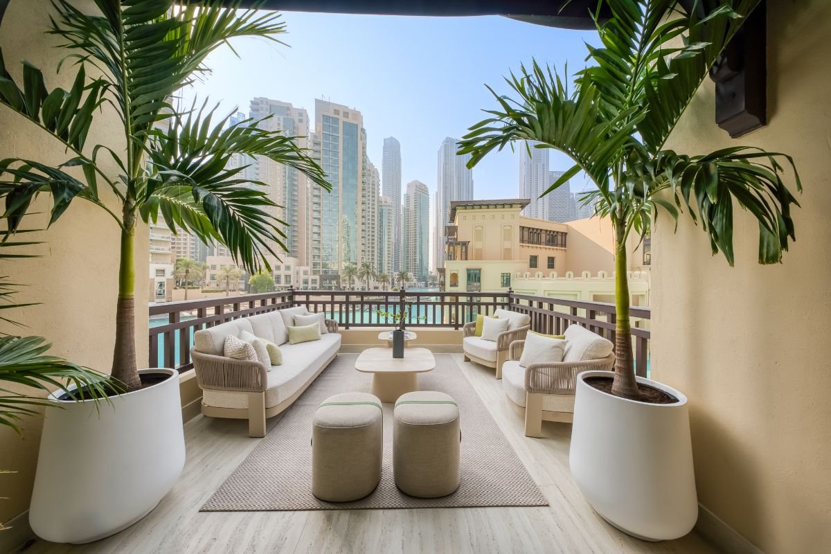 Luxury outdoor lounge with cream sofas, coffee tables and potted palm trees overlooking Downtown Dubai.