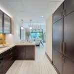 Bespoke kitchen with dark wood cabinetry, marble worktops and pendant lighting opening towards the dining area.