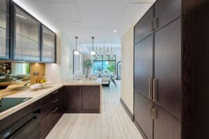 Bespoke kitchen with dark wood cabinetry, marble worktops and pendant lighting opening towards the dining area.
