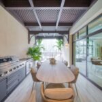 Covered outdoor dining terrace featuring a long dining table, built-in barbecue and timber pergola.