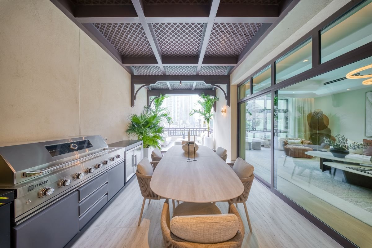 Covered outdoor dining terrace featuring a long dining table, built-in barbecue and timber pergola.
